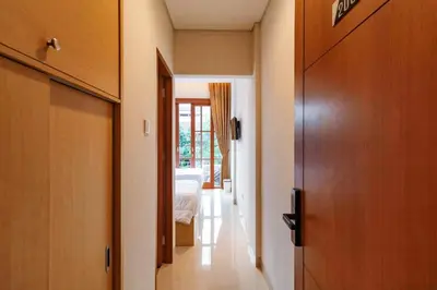 a hallway with a room with a bed and a door at AA Inn Kuta Beach in Ngurah Rai International Airport