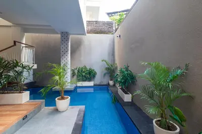 a swimming pool in the middle of a building with plants at AA Inn Kuta Beach in Ngurah Rai International Airport
