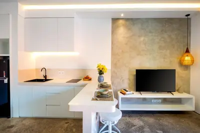 a kitchen with white cabinets and a tv on a counter at Harmoni Lane Studios in Seminyak