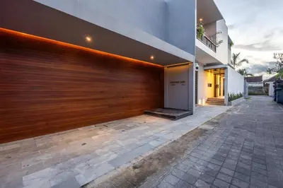 a house with a wooden garage door and a patio at Harmoni Lane Studios in Seminyak