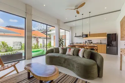 a living room with a green couch and a kitchen at VILLA BIBA cosy and stylish in Canggu