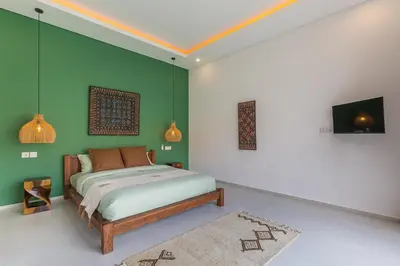 a bedroom with a bed and a green wall at VILLA BIBA cosy and stylish in Canggu