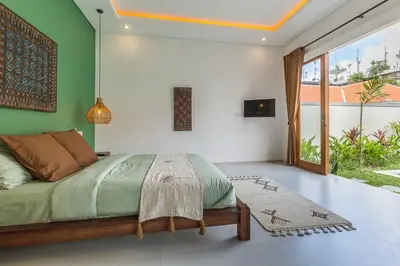 a bedroom with a bed with green and white walls at VILLA BIBA cosy and stylish in Canggu