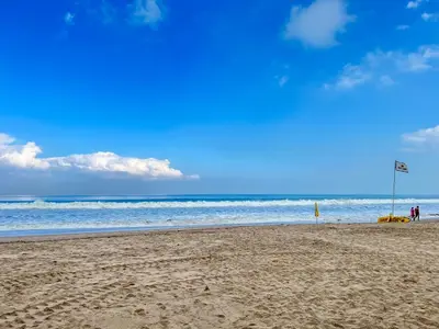 a beach with a flag in the sand and the ocean at Apartment at Jayakarta Residence Beach Front Access in Seminyak