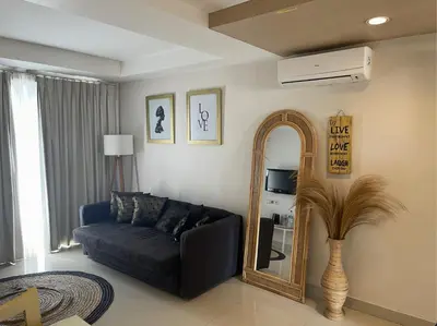 a living room with a couch and a mirror at Apartment Keluarga di Kuta Bali in Kuta
