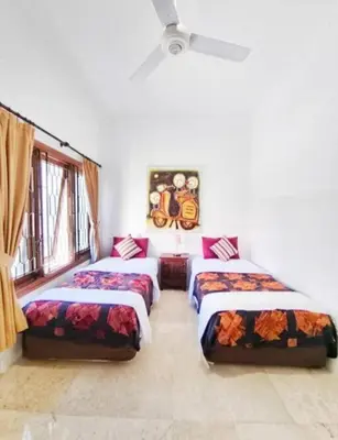 a room with three beds and a window at Villa Mimi Mesari Kuta Bali in Kuta