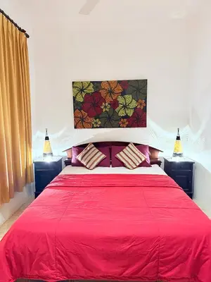 a bedroom with a red bed with two lamps at Villa Mimi Mesari Kuta Bali in Kuta