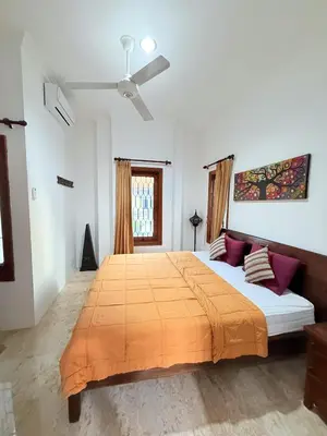 a bedroom with a large bed with an orange blanket at Villa Mimi Mesari Kuta Bali in Kuta