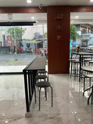 a restaurant with tables and chairs and a window at Hotel Sanrina Kuta Bali in Kuta