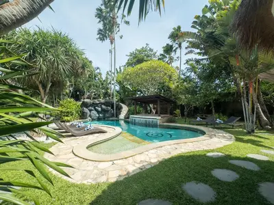 a swimming pool in a yard with palm trees at Villa Santai by Optimum Bali Villas in Canggu