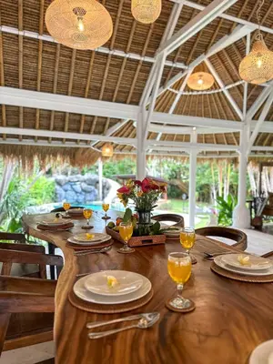 a wooden table with plates and wine glasses on it at Villa Santai by Optimum Bali Villas in Canggu