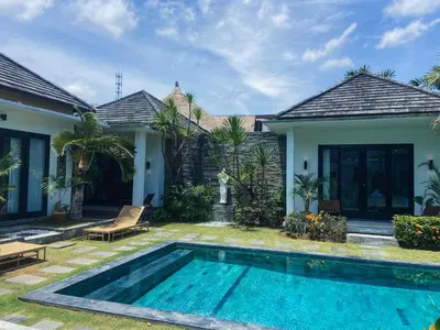 a villa with a swimming pool in front of a house at Splendid 3 BR villa with large pool and garden in Canggu
