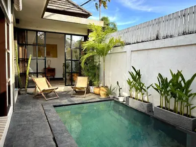 a swimming pool in a backyard with chairs and plants at Villa Omarama Seminyak Beach in Seminyak