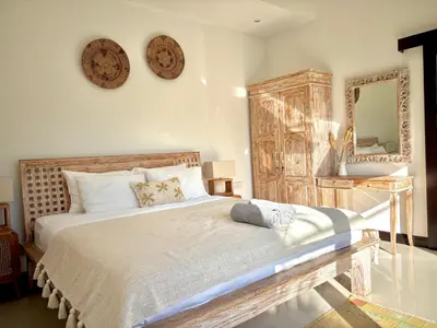 a bedroom with a large bed and a mirror at Villa Omarama Seminyak Beach in Seminyak
