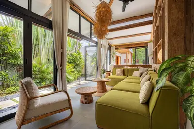 a living room with green furniture and large windows at Villa Sebelah by Optimum Bali Villas in Seminyak