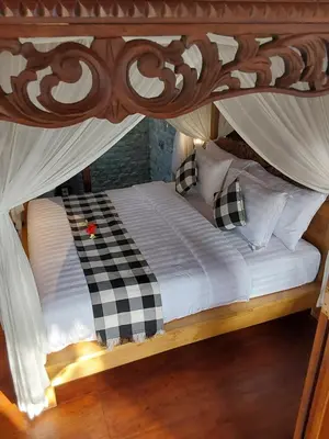 a bed with a canopy with checkered pillows at Navalia Rumah Kayu in Kerobokan
