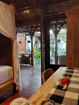 a dining room with a table and a bed at Navalia Rumah Kayu in Kerobokan