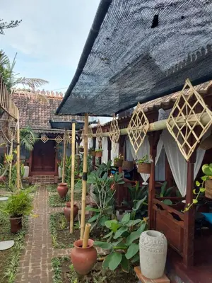 a house with a thatched roof with plants in a courtyard at Navalia Rumah Kayu in Kerobokan