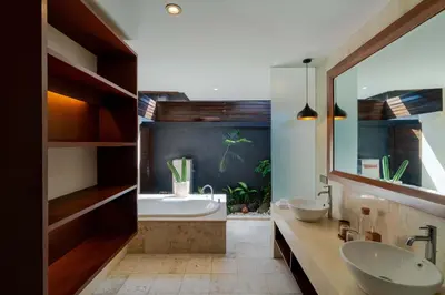 a bathroom with two sinks and a tub with a plant on the wall at Boholuma Villas by Pertama Management in Seminyak