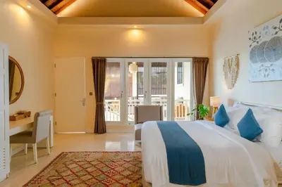 a hotel room with a bed and a desk and a window at Boholuma Villas by Pertama Management in Seminyak
