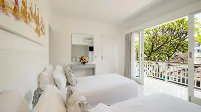 a white bedroom with two beds and a balcony at Villa Alun by Villa Finder in Canggu