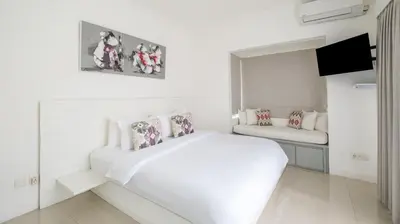 a white bedroom with a bed and a couch at Villa Alun by Villa Finder in Canggu