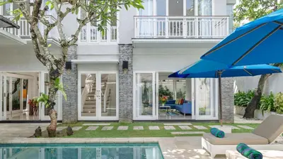 a house with a pool and a blue umbrella at Villa Alun by Villa Finder in Canggu
