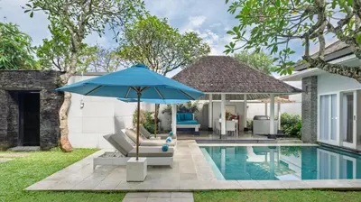 a blue umbrella sitting next to a swimming pool at Villa Alun by Villa Finder in Canggu