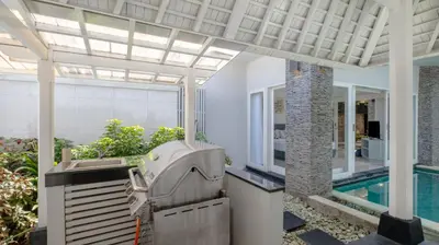 an outdoor kitchen with a grill and a swimming pool at Villa Alun by Villa Finder in Canggu