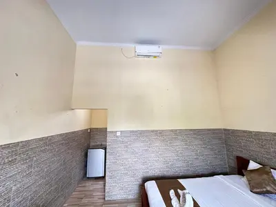a bedroom with a bed and a small refrigerator at Osa Guest House 5 in Seminyak