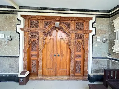 a large wooden door in a brick building at Osa Guest House 5 in Seminyak