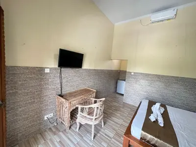 a room with a bed and a table and a tv at Osa Guest House 5 in Seminyak