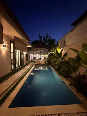 a swimming pool in the backyard of a house at night at Villa Majegau 3, 3 bedrooms, Seminyak center in Seminyak