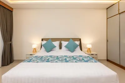 a bedroom with a large white bed with blue pillows at The Saren CoLiving by SooBali in Kerobokan