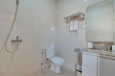 a white bathroom with a toilet and a shower at Stylish 3BR Villa Sandalwood near Beach in Seminyak
