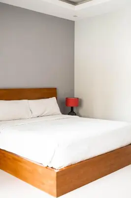 a bedroom with a bed with white sheets and a red lamp at Bali Bliss Residence in Seminyak