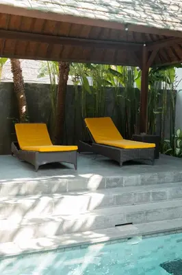 two yellow chairs sitting under a gazebo next to a pool at Bali Bliss Residence in Seminyak