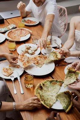 a group of people sitting around a table eating pizza at Jiva Flow Kerobokan in Kerobokan