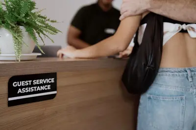 a woman with a guest service assistance sign on a counter at Jiva Flow Kerobokan in Kerobokan