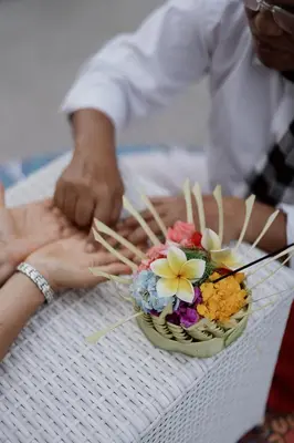 a person holding a bowl of flowers on a table at Jiva Flow Kerobokan in Kerobokan
