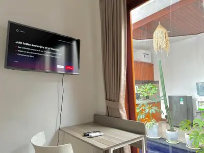 a living room with a table and a tv on the wall at CWB Villa in Kerobokan