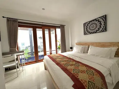 a bedroom with a bed and a desk and a window at CWB Villa in Kerobokan