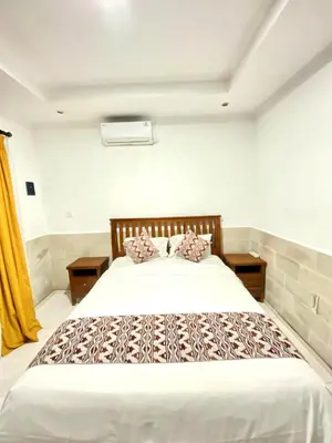 a bedroom with a large white bed with two pillows at Karna Guest House in Seminyak
