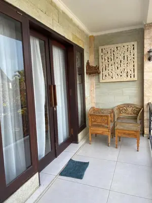a porch with a pair of chairs and a window at Karna Guest House in Seminyak
