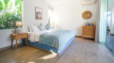 a bedroom with a bed with a nightstand and a table at Desa Berawa Beach Villa No13 in Canggu