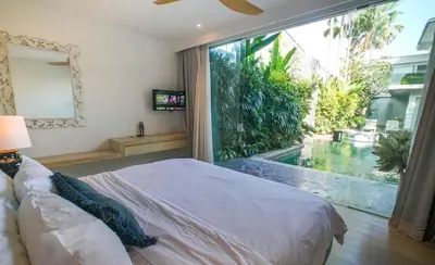 a bedroom with a bed and a large window at Desa Berawa Beach Villa No13 in Canggu