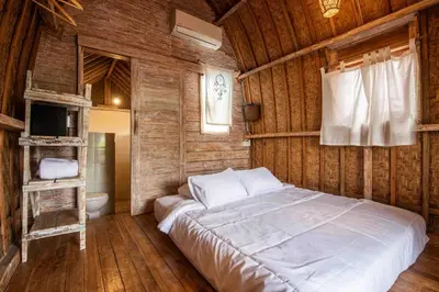 a bedroom with a large bed in a wooden wall at Little Farm House Kerobokan near Seminyak in Kerobokan