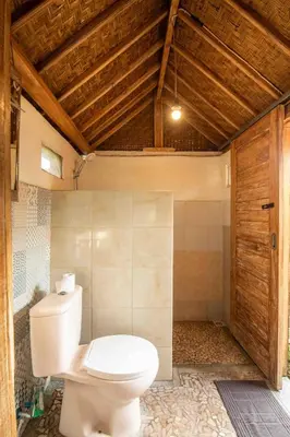 a bathroom with a toilet and a wooden door at Little Farm House Kerobokan near Seminyak in Kerobokan