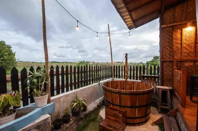 a porch with a large wooden barrel and a fence at Little Farm House Kerobokan near Seminyak in Kerobokan