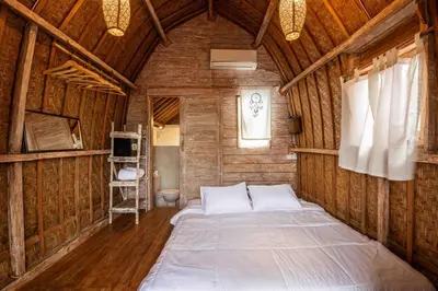 a bedroom with a large bed in a wooden wall at Little Farm House Kerobokan near Seminyak in Kerobokan